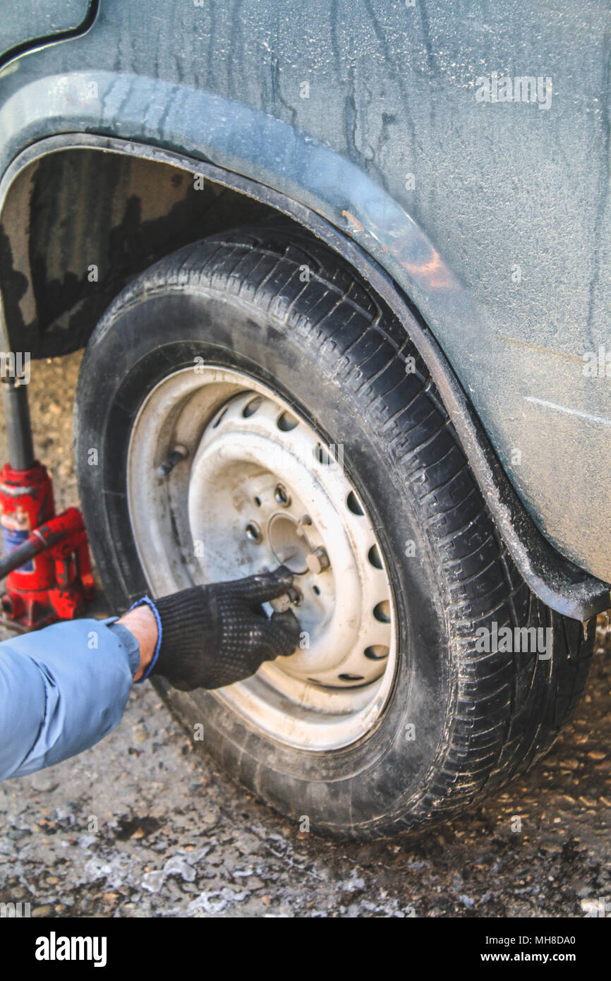 Replacing lug nuts by hand while changing tires on a vehicle Stock