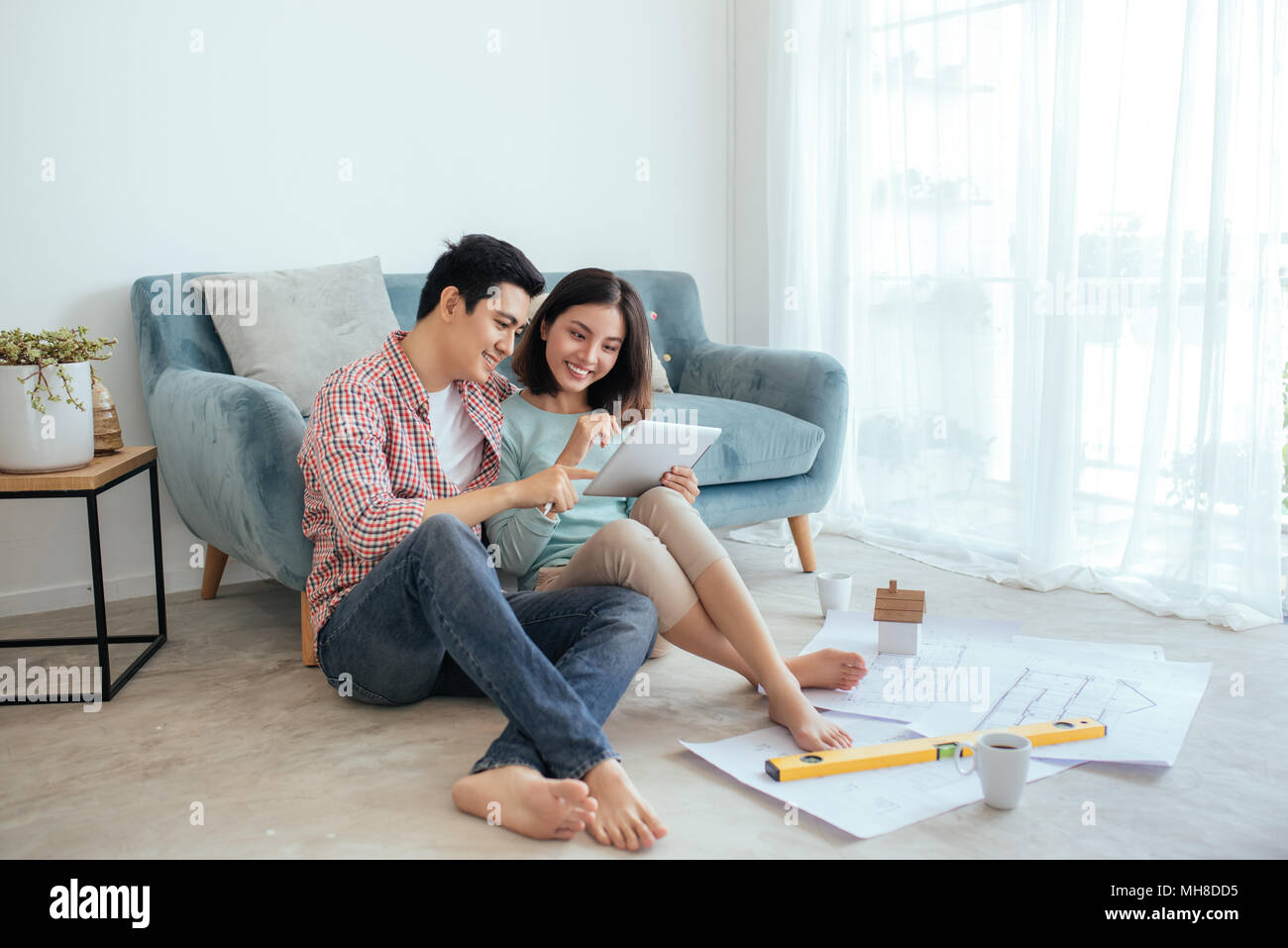 Attractive young asian adult couple looking at house plans. Stock Photo