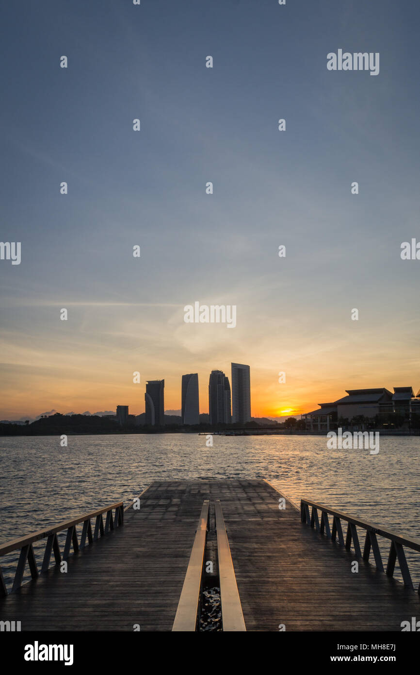 Sun creeping behind the city under the wide blue sky, Malaysia. Stock Photo