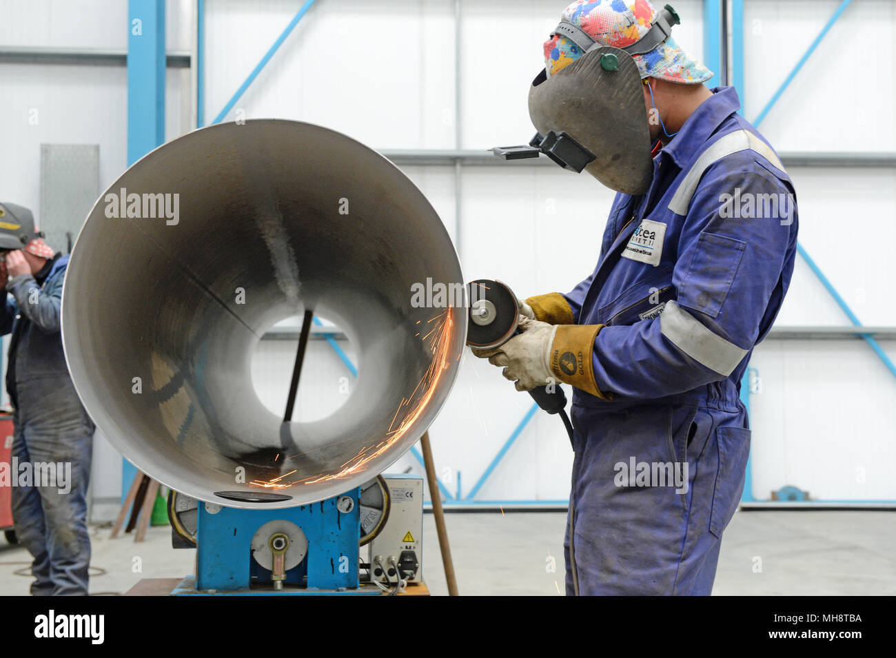 Man cutting large pipe with grinder in engineering workshop Stock Photo