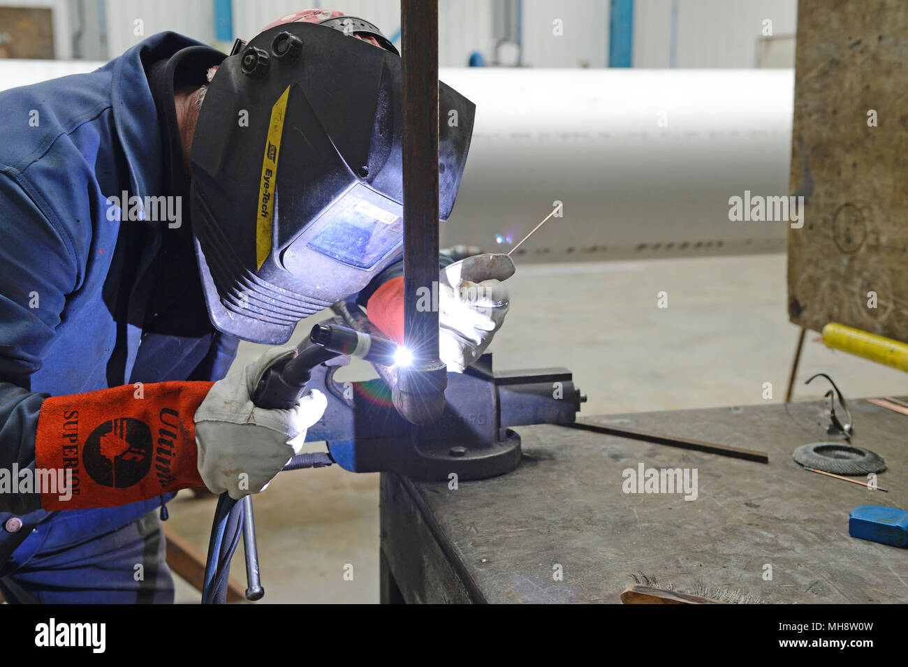 Welder welding pipe together in a fabrication workshop Stock Photo