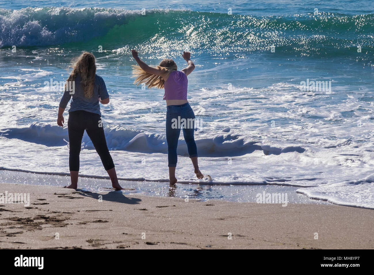 Two girls enjoying themselves paddling in the sea at Fistral Beach in Newquay in Cornwall. Stock Photo