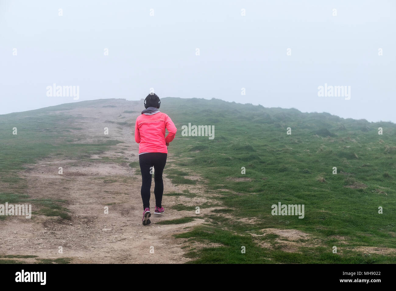 A runner on a track on Pentire Point East Headland in sea mist, Cornwall Stock Photo