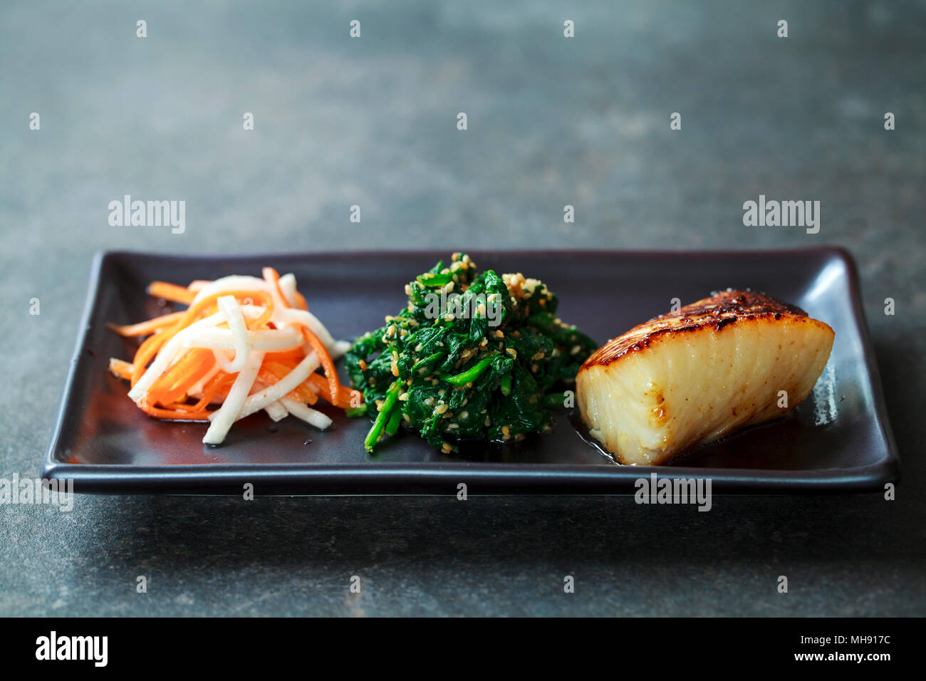 Miso marinated black cod with Japanese spinach salad gomaae Stock Photo