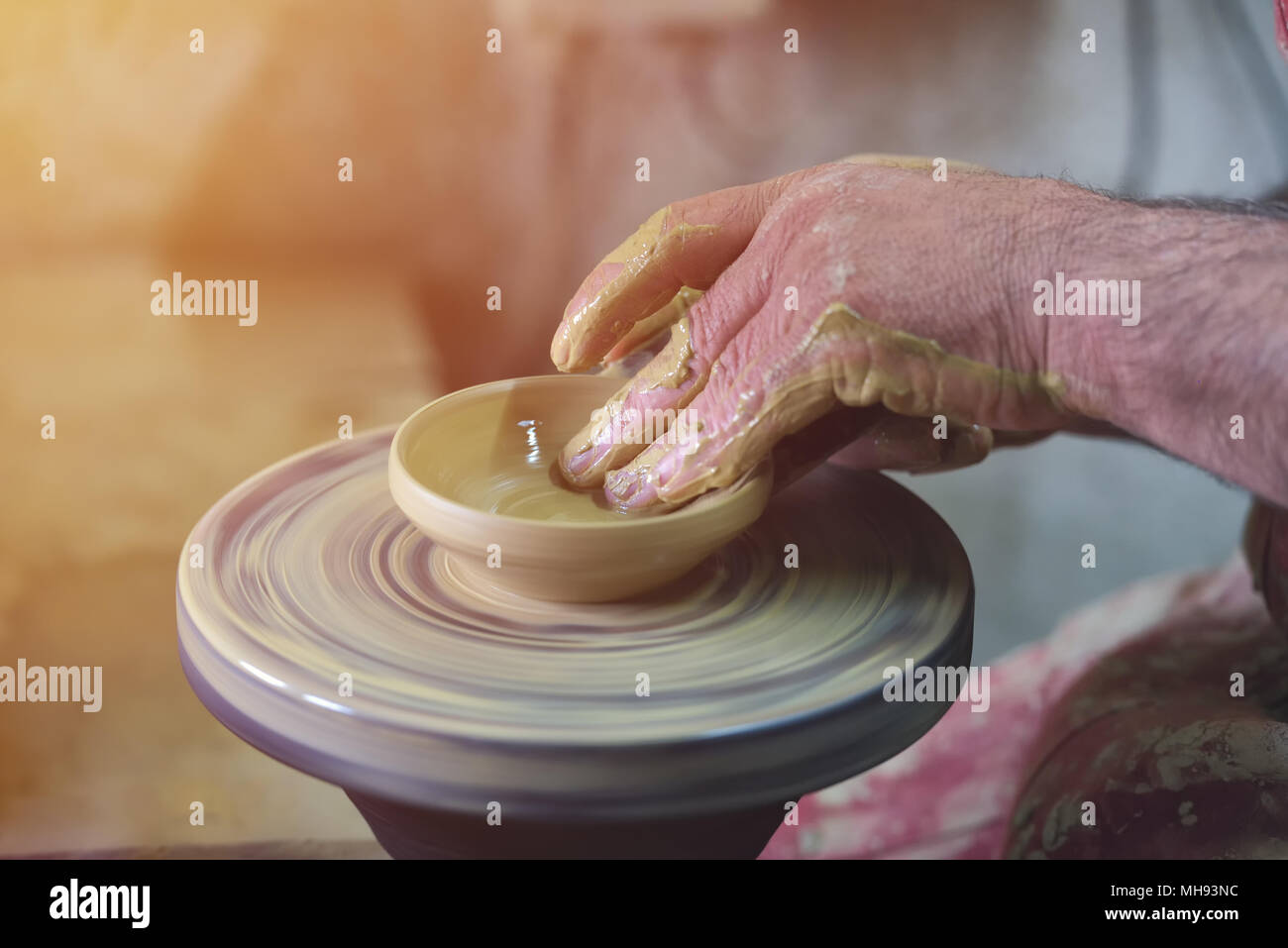 Creating a jar or vase of white clay close-up. Man hands, pottery, workshop, ceramics art concept. Twisted potter's wheel Stock Photo