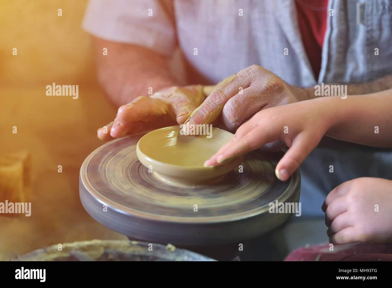 Creating a jar or vase of white clay close-up. Grandpa teaches grandson pottery, workshop, ceramics art concept. Twisted potter's wheel Stock Photo