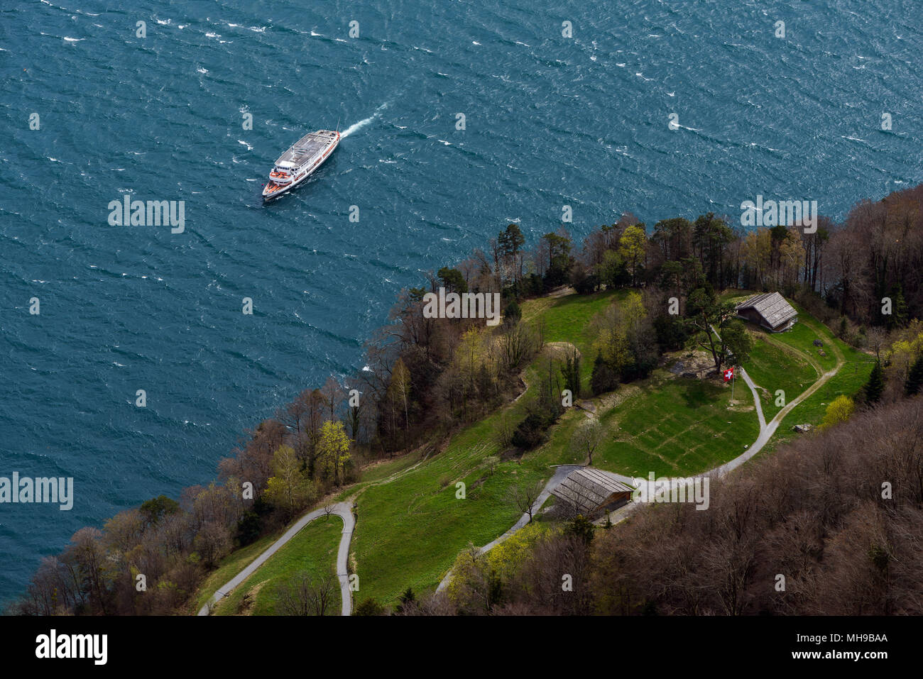 Top view from Schiller's balcony on historical Rütli meadow with Swiss flag and approaching ship on a sunny and windy day Stock Photo