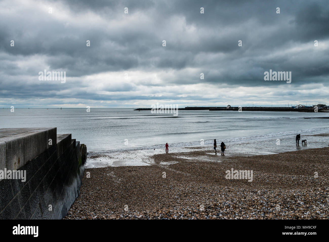 A view of the Cobb in Lyme Regis with people on the shingle beach Stock ...