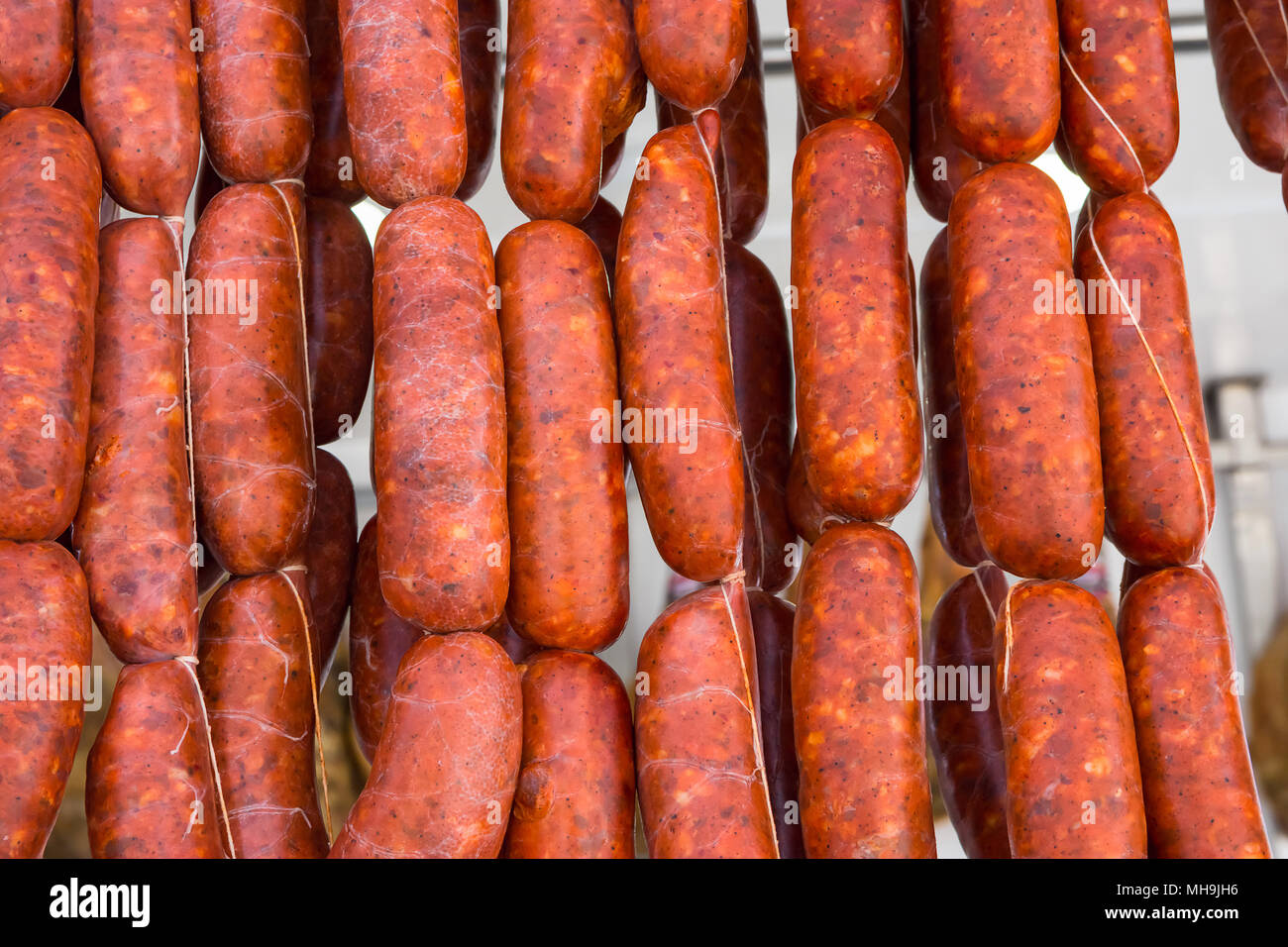 Strings of Hand Crafted Artisanal Sausages Red Chorizo Hanging at Farmers Market. Traditional