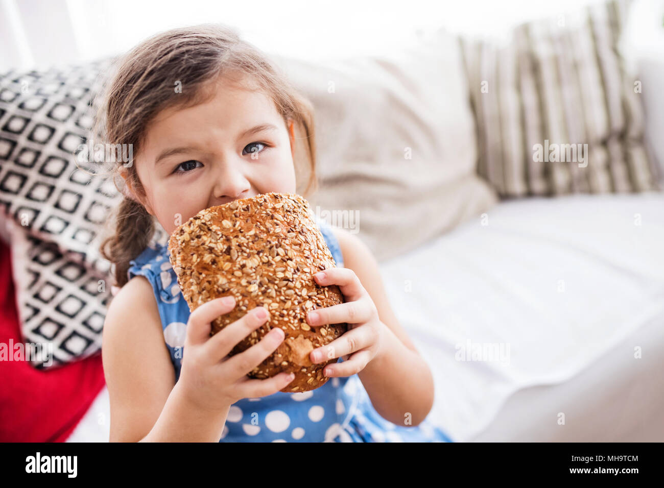 A small girl at home eating a loaf of bread Stock Photo Alamy