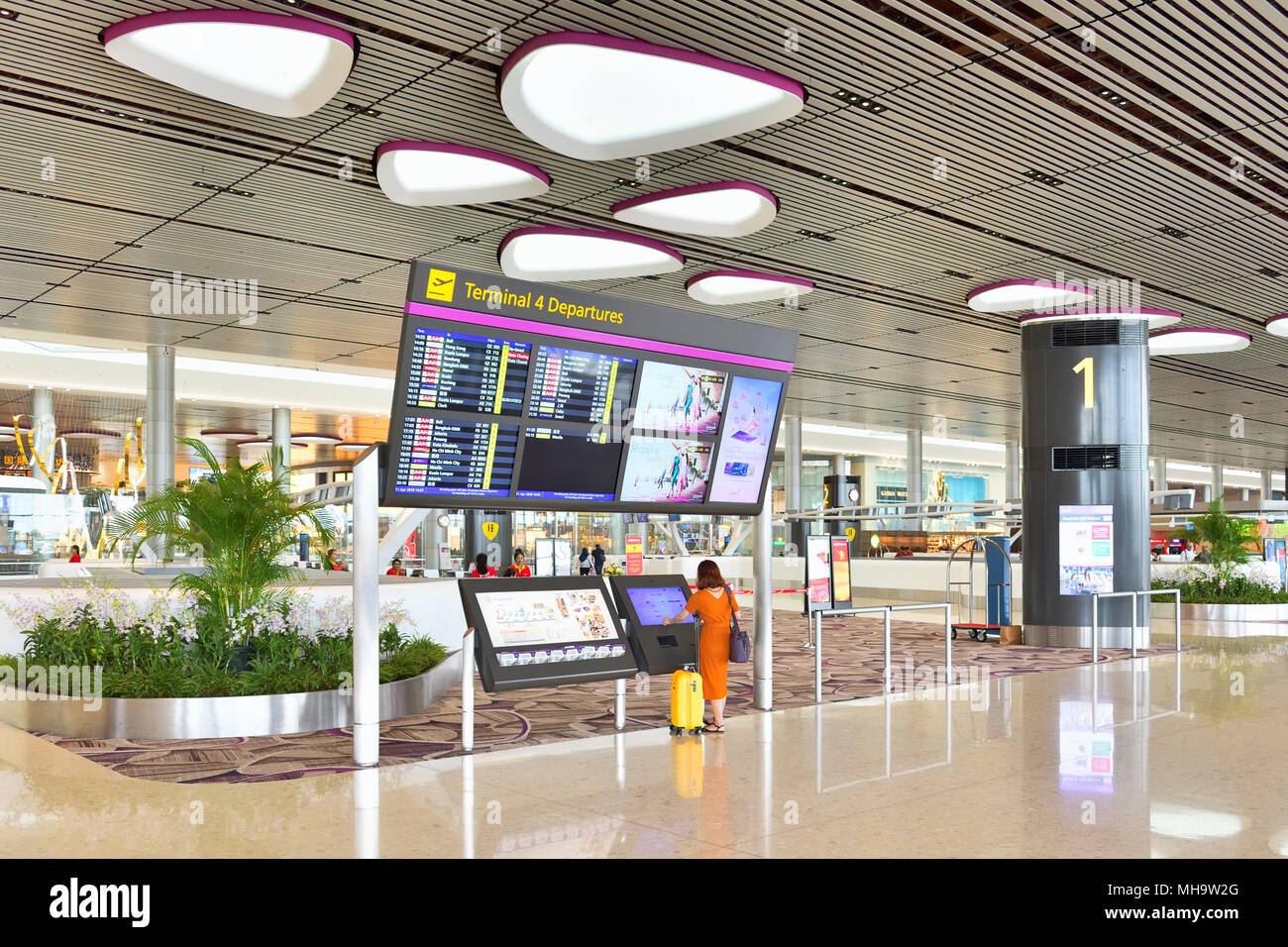 Singapore Changi International Airport, Terminal 4. A solo traveller checks out the flight departure information on a display. Stock Photo