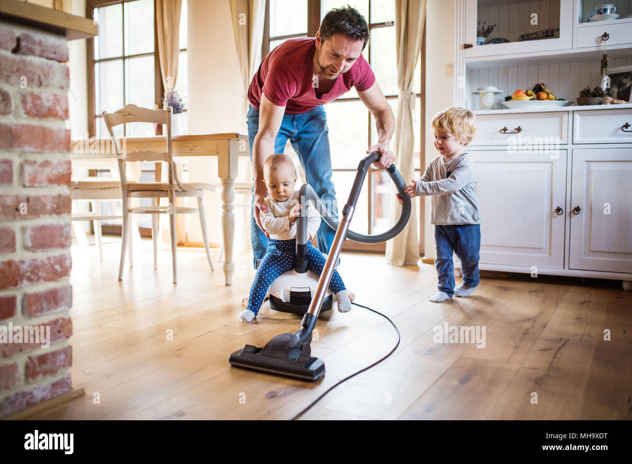 Father and two toddlers doing housework. Stock Photo