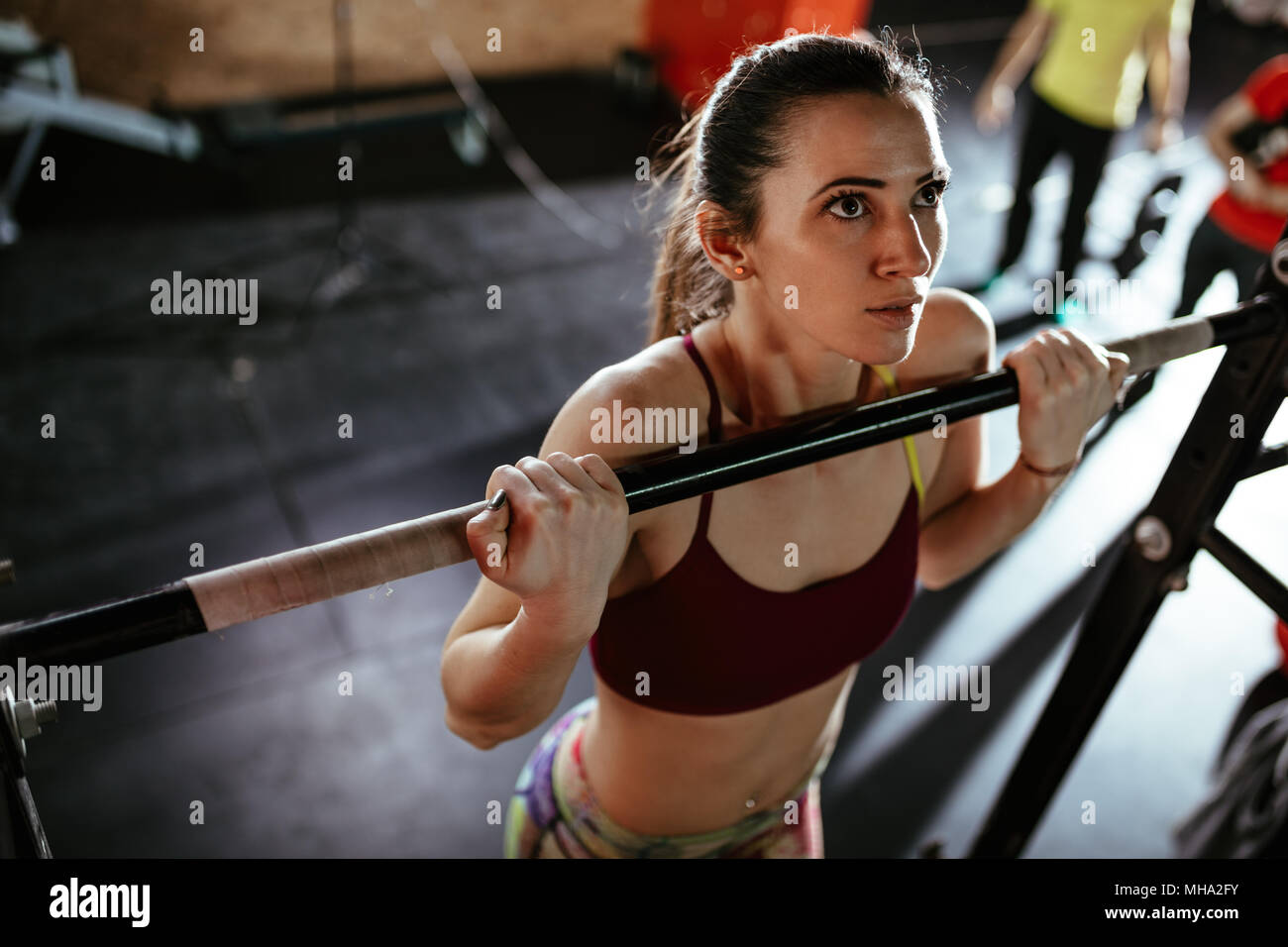 Beautiful young strong muscular woman doing pull-up exercise at the gym ...