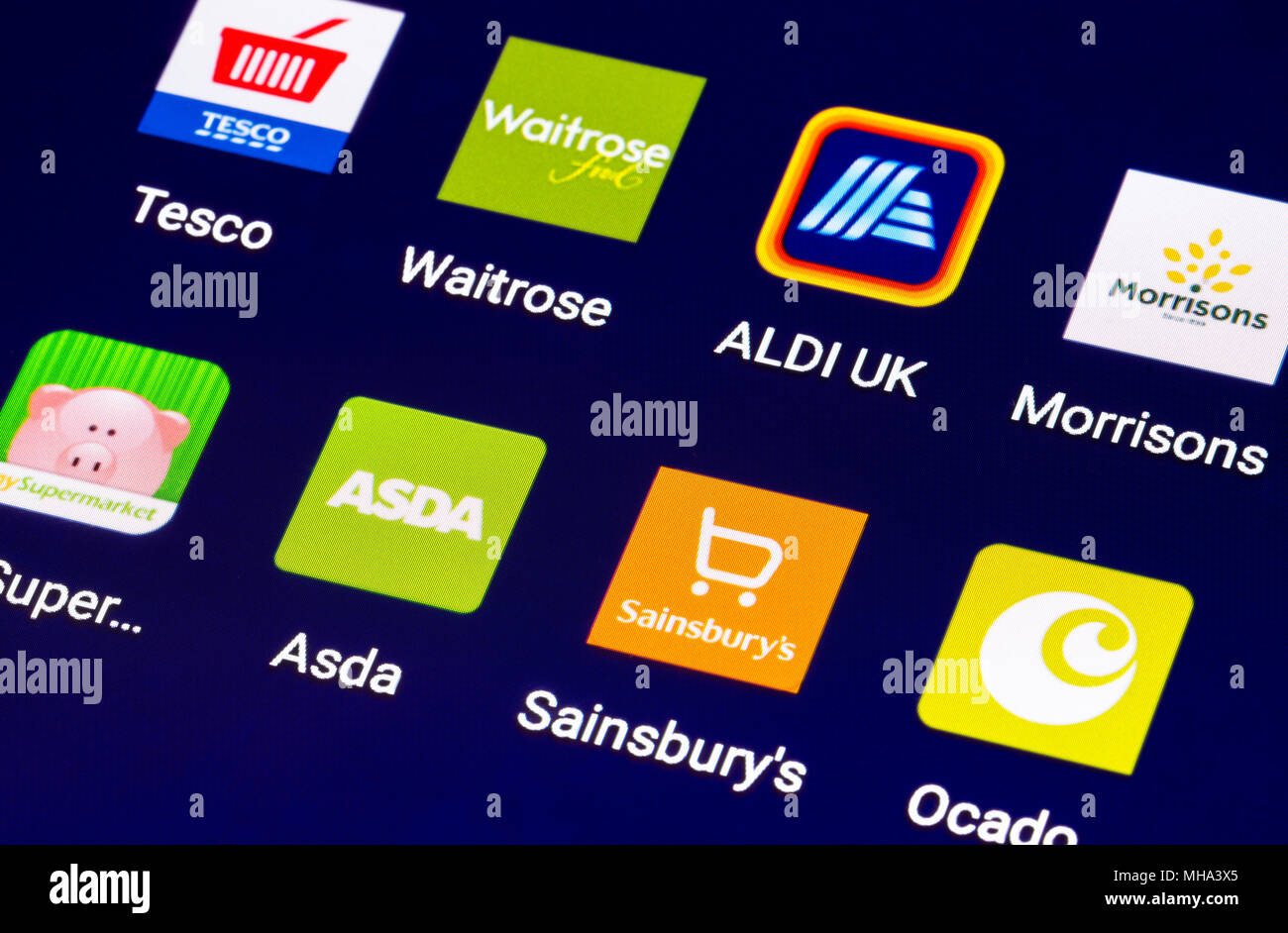 Icons on a tablet for online food shops in the UK. Grocery shopping online on a mobile device. Modern Internet shopping shortcuts for grocery stores.. Stock Photo