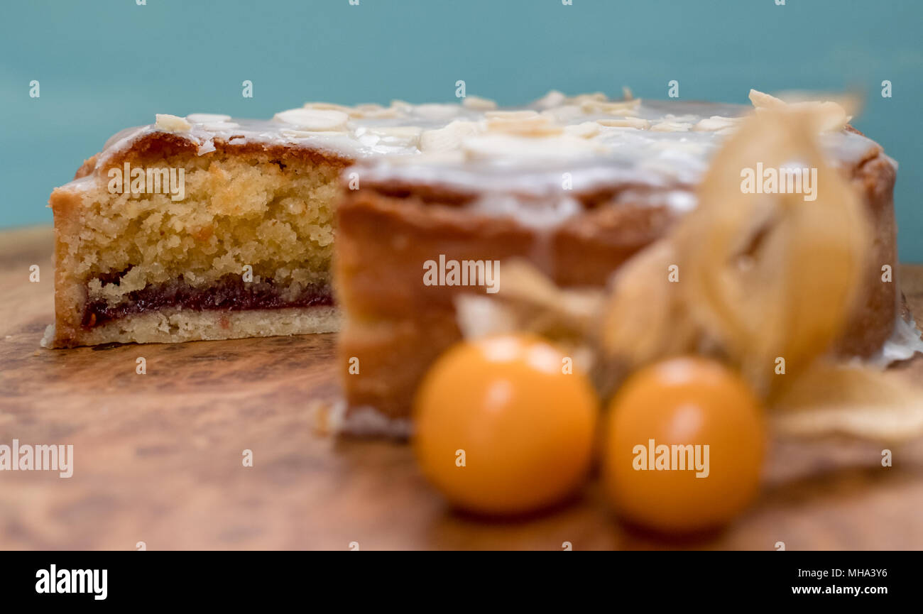 Sliced bakewell tart cake on olive wood platter with aqua blue