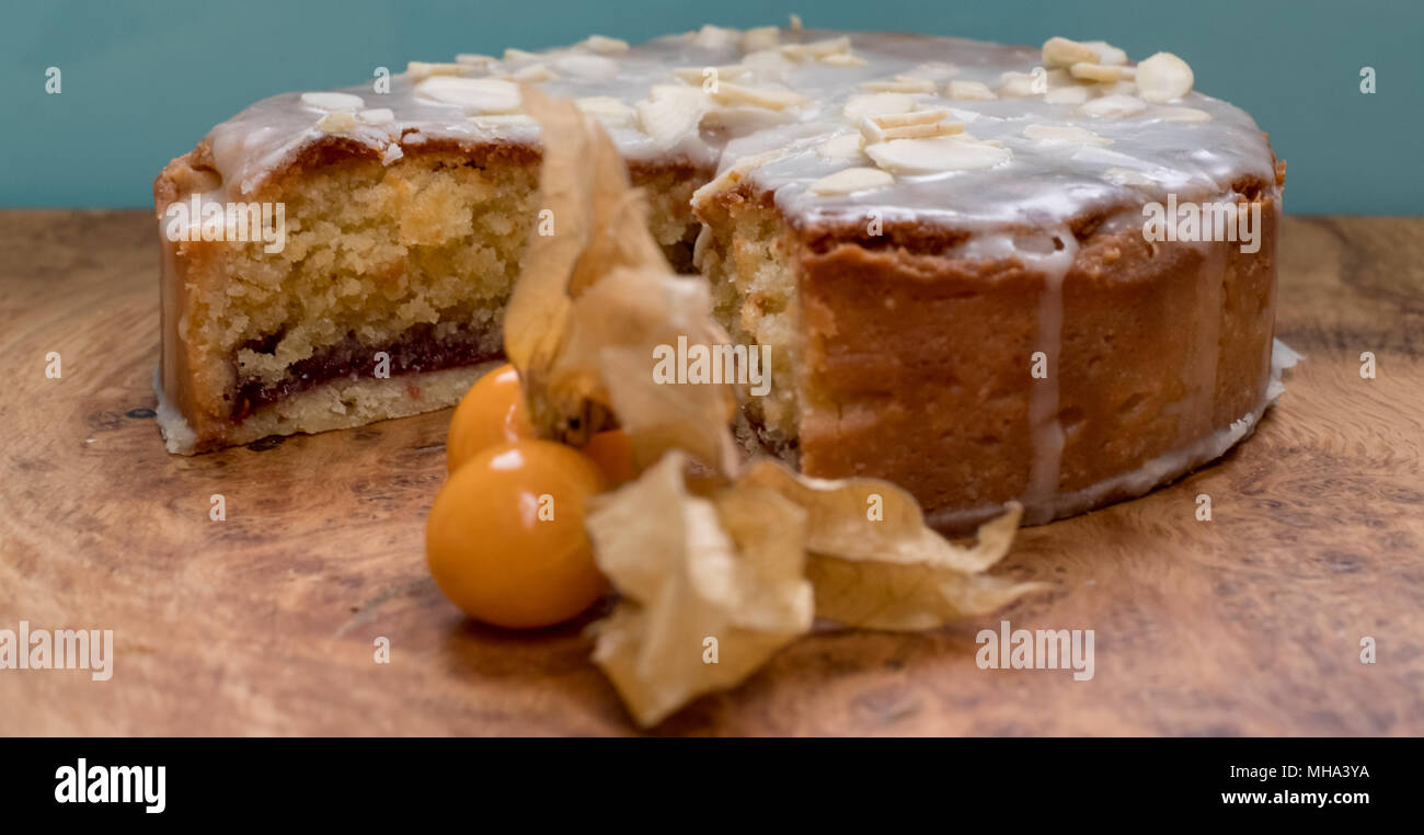 Sliced bakewell tart cake on olive wood platter with aqua blue