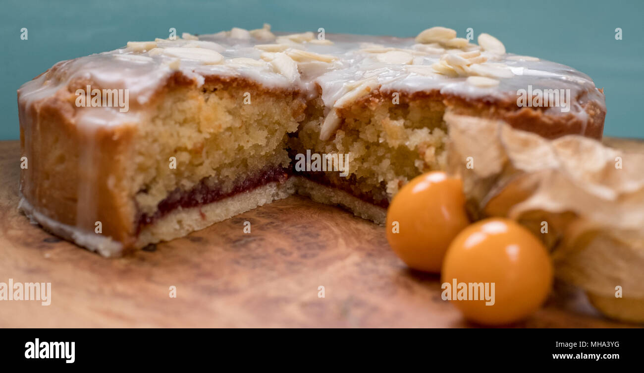 Sliced bakewell tart cake on olive wood platter with aqua blue