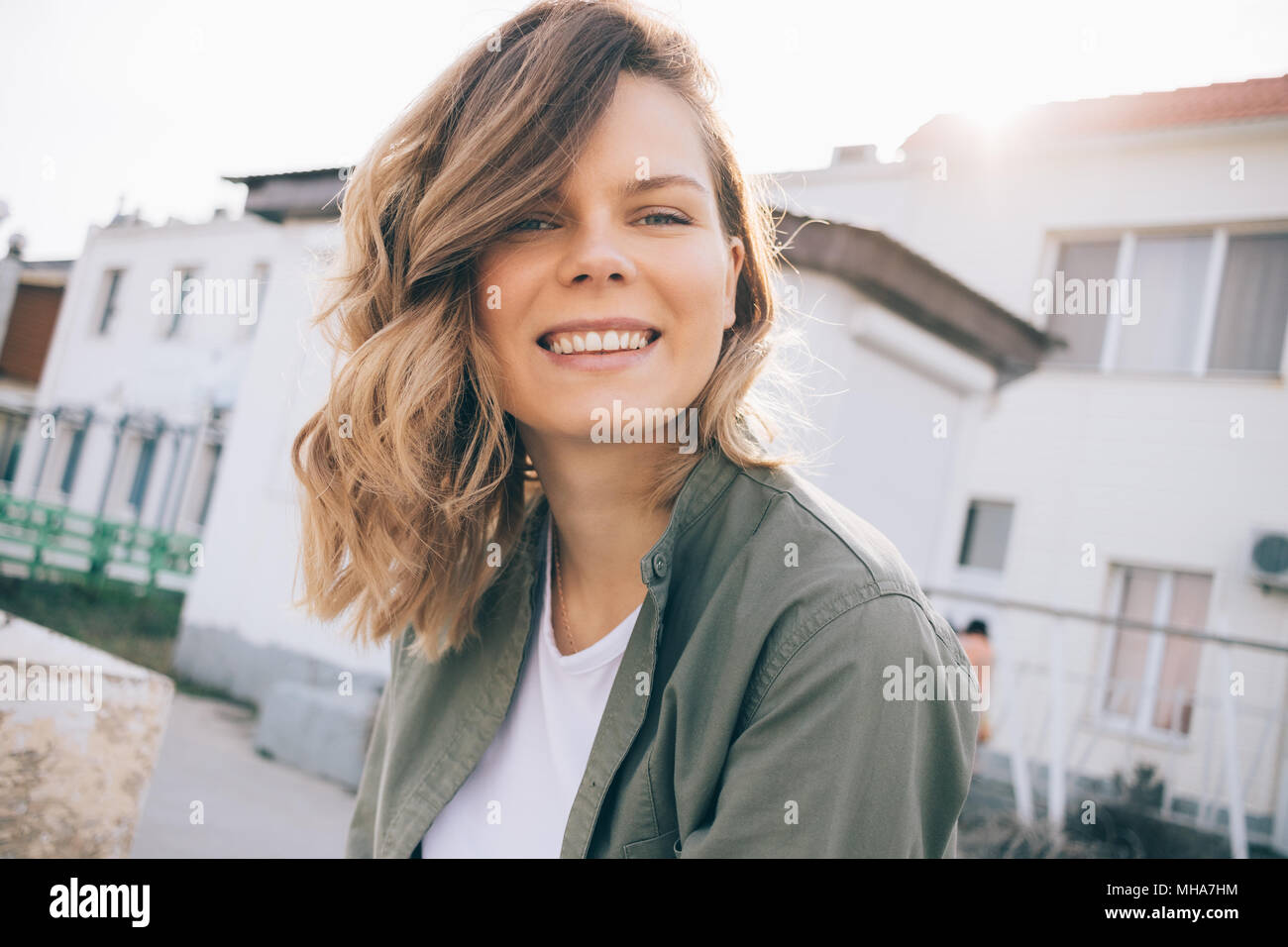 Portrait of a beautiful smiling young woman with curly hair in sunlight ...