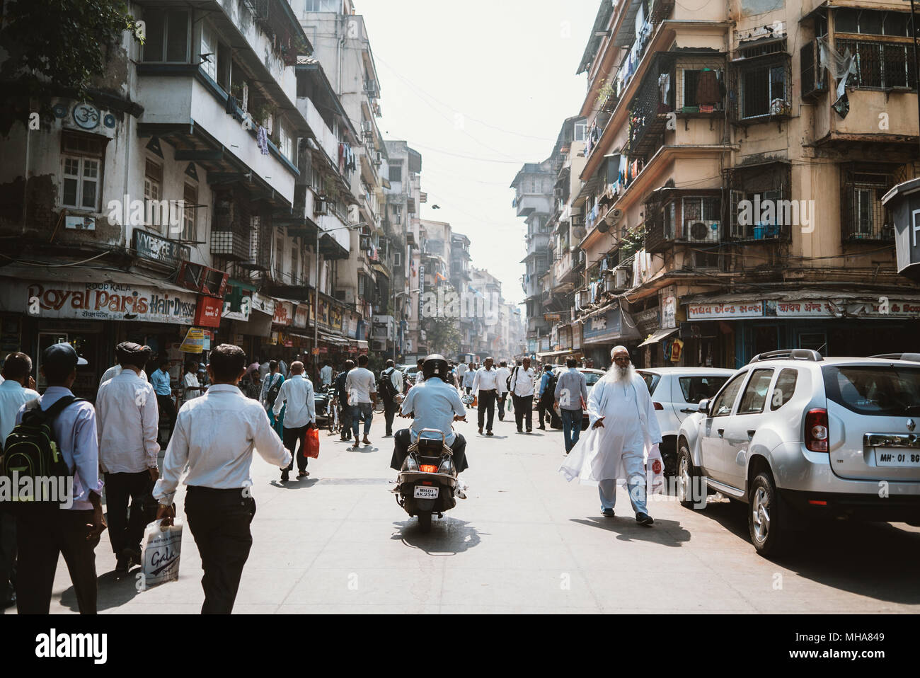 a busy street during rush hour in Mumbai, India with lots of pedestrians and scooters. Stock Photo