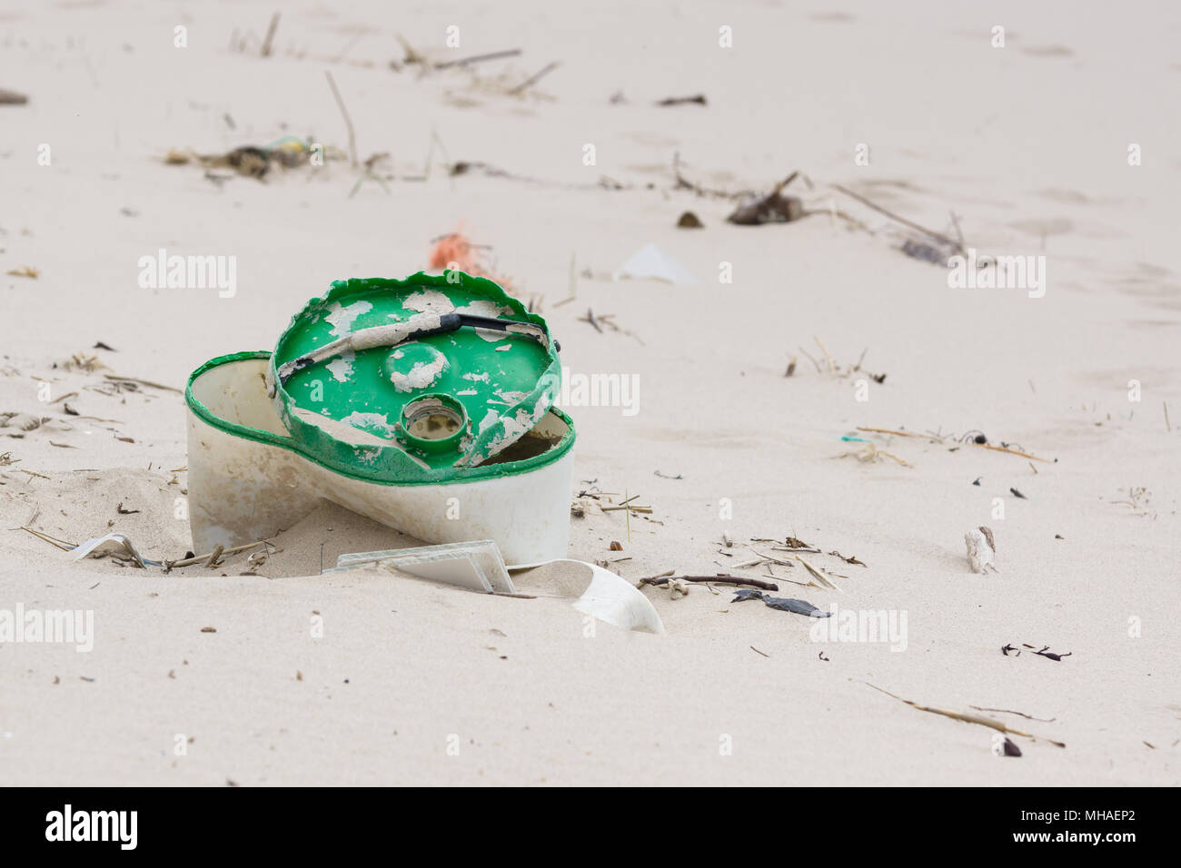 Plastic rubbish washed up on a beach and part buried in the sand an example of the many pieces of garbage in the sea around the world Stock Photo