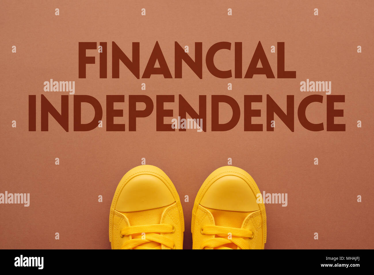 Financial independence concept, young person in yellow sneakers standing over the text, top view Stock Photo