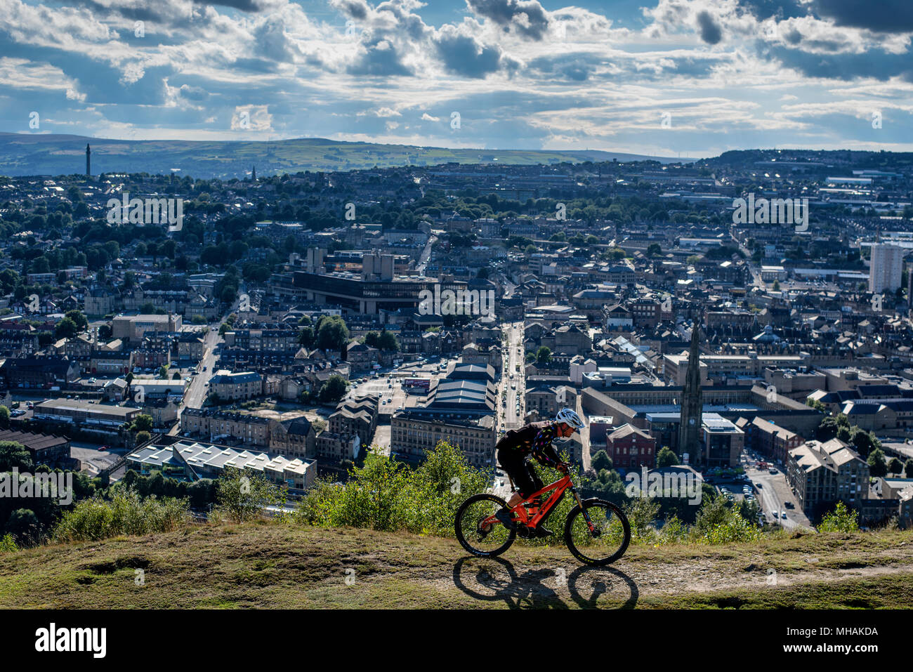 A man rides an electric pedal assist e-bike overlooking the town of Halifax in northern England. Stock Photo