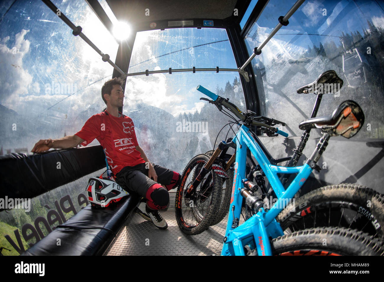 A mountain biker sits in Le Pleney gondola ski lift with bikes in the