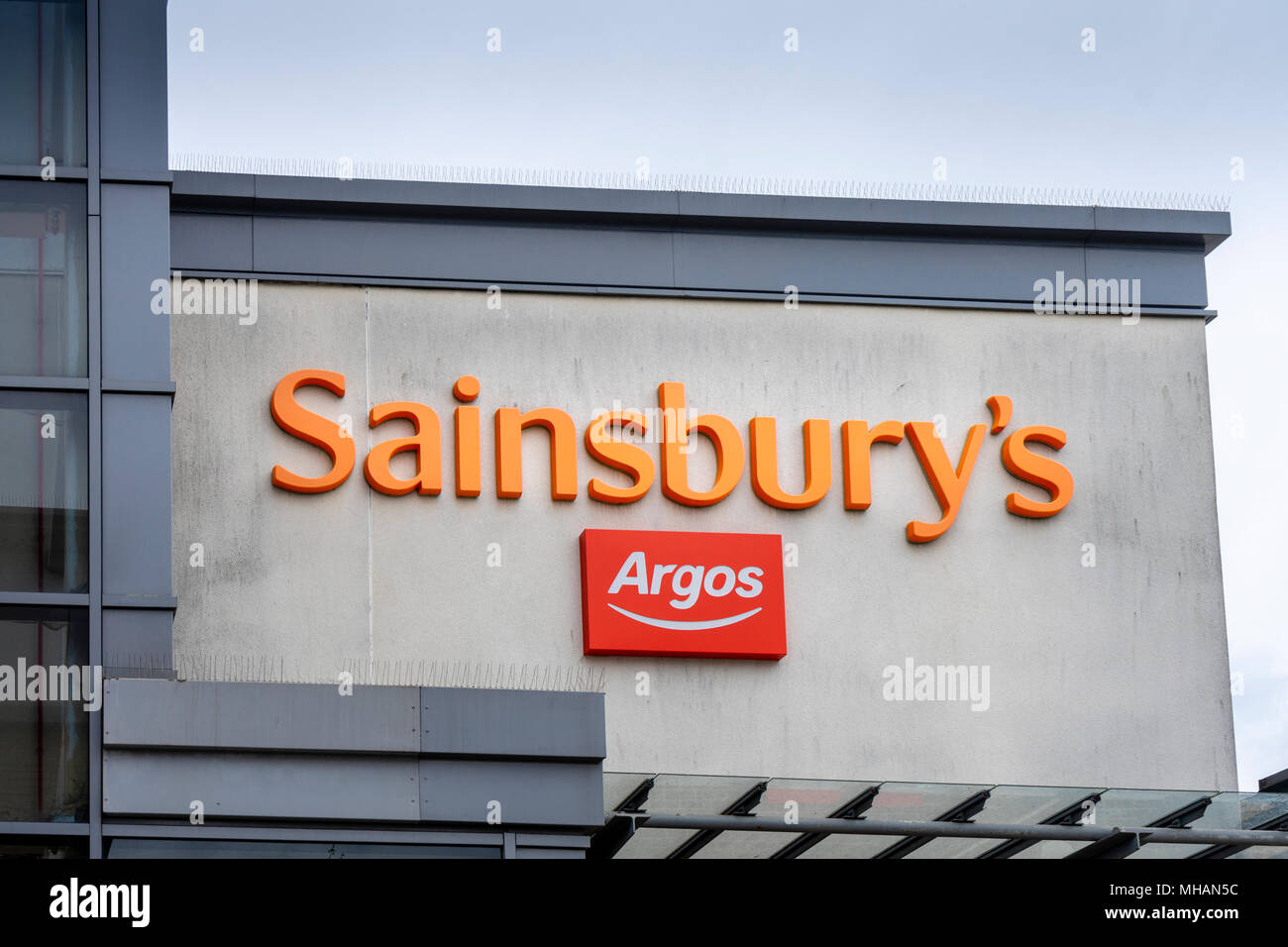 An orange Sainsbury's and red sign - the two retailers have merged in 2016 Stock Photo