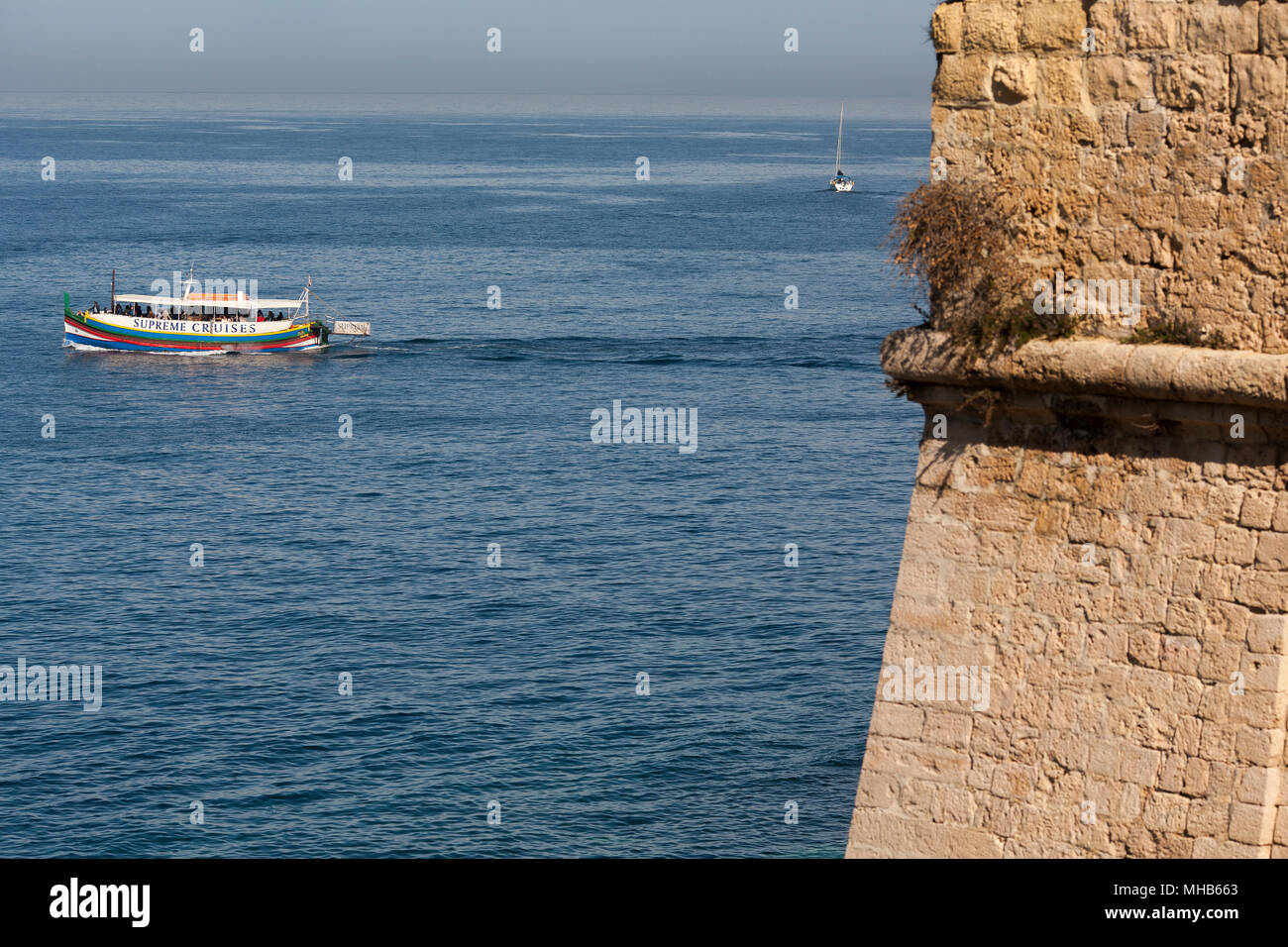 A harbour tour boat passes the ancient battlements of Valletta, Malta Stock Photo