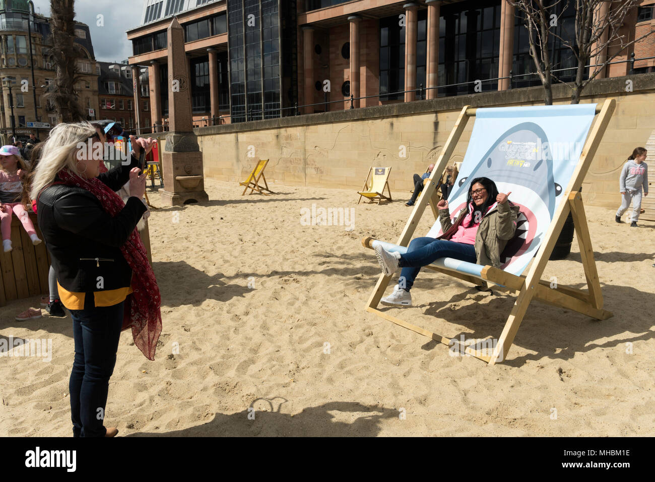 Smiling woman sitting on oversized deckchair Newcastle Quayside Seaside, north east England,  UK Stock Photo