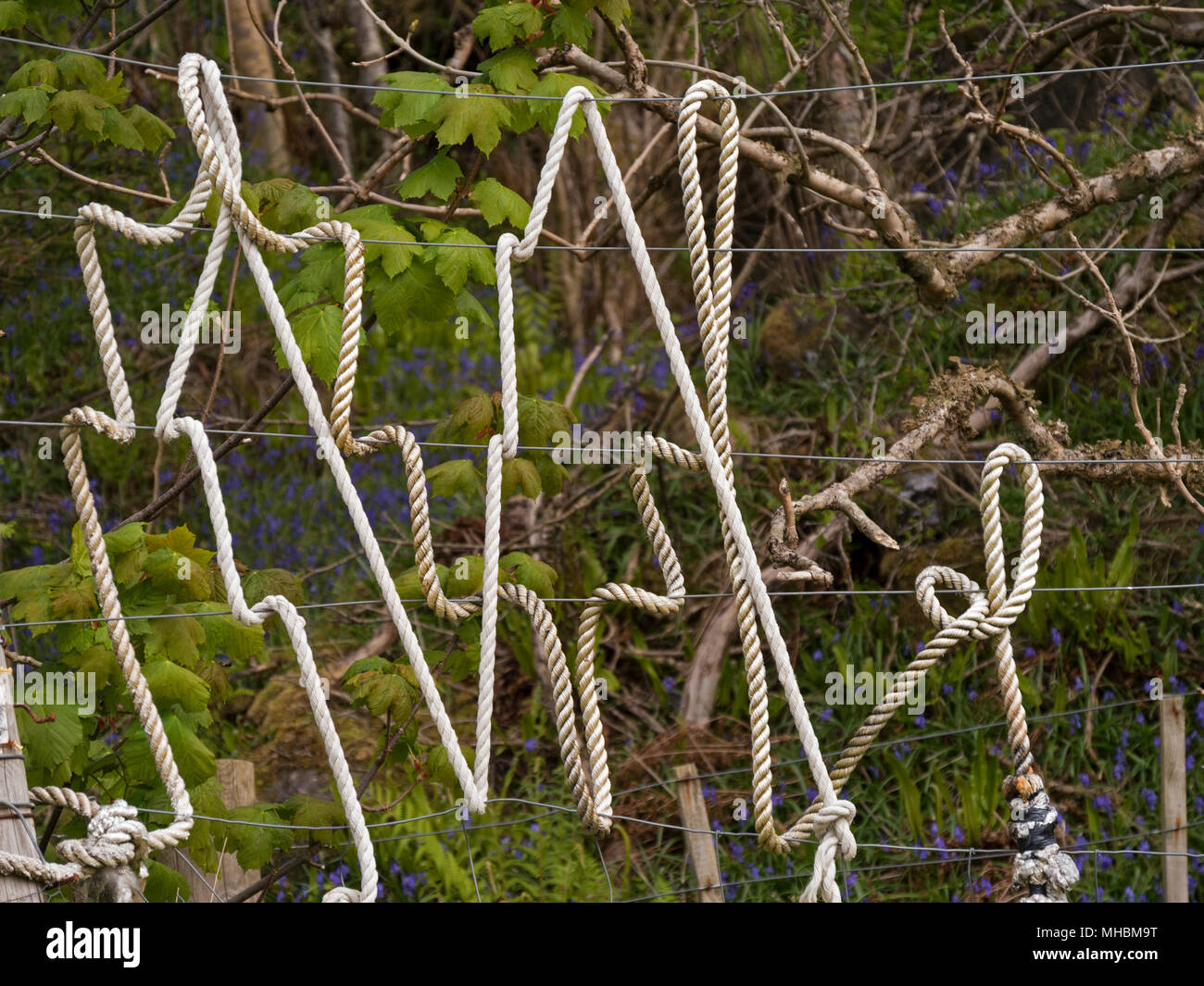 Old discarded white nylon rope wrapped around wire fence to create random artistic pattern Stock Photo