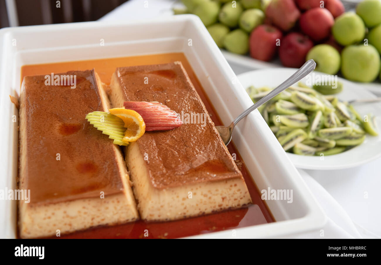 Fresh delicious caramel cake on a white plate with honey sauce and fruit garnishes. Stock Photo