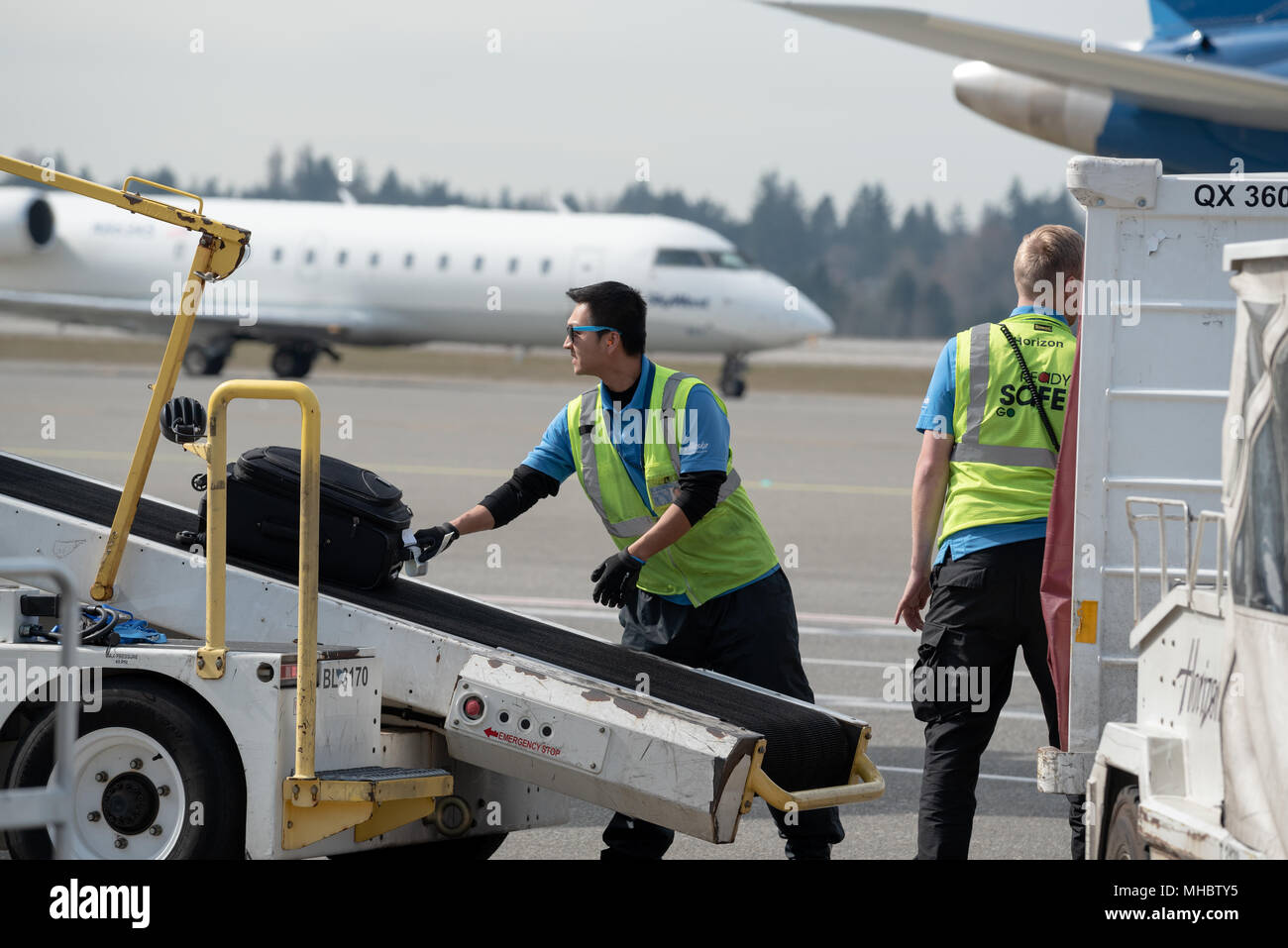 Ramp agents unloading baggage from an airplane at Seattle–Tacoma International Airport, Washington. Stock Photo