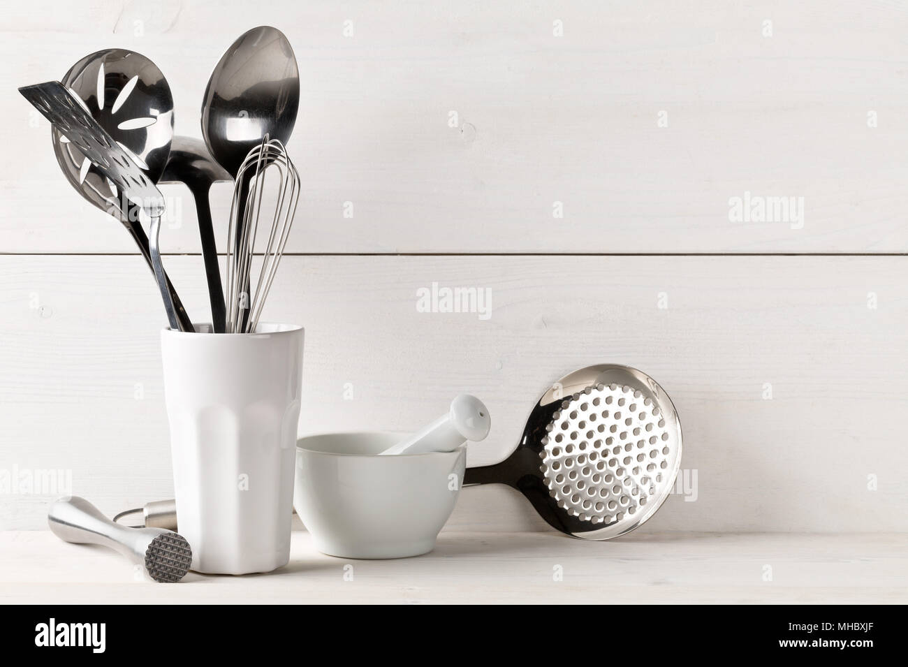 https://c8.alamy.com/comp/MHBXJF/kitchen-cooking-utensils-in-white-cup-with-pestle-and-mortar-on-white-table-with-white-wooden-board-background-MHBXJF.jpg