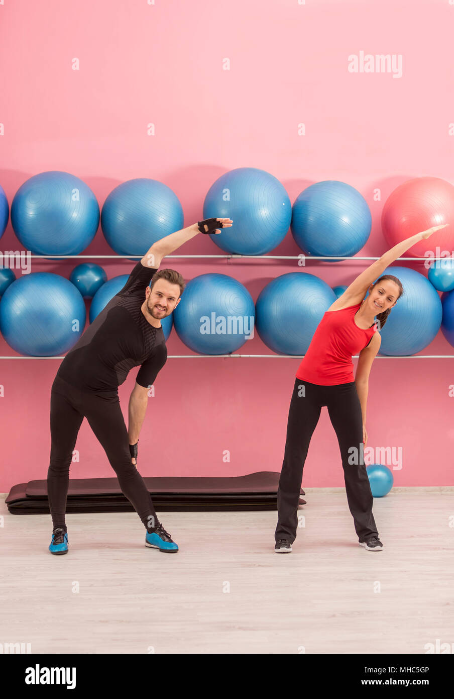 Young couple doing stretching exercises in a gym Stock Photo - Alamy