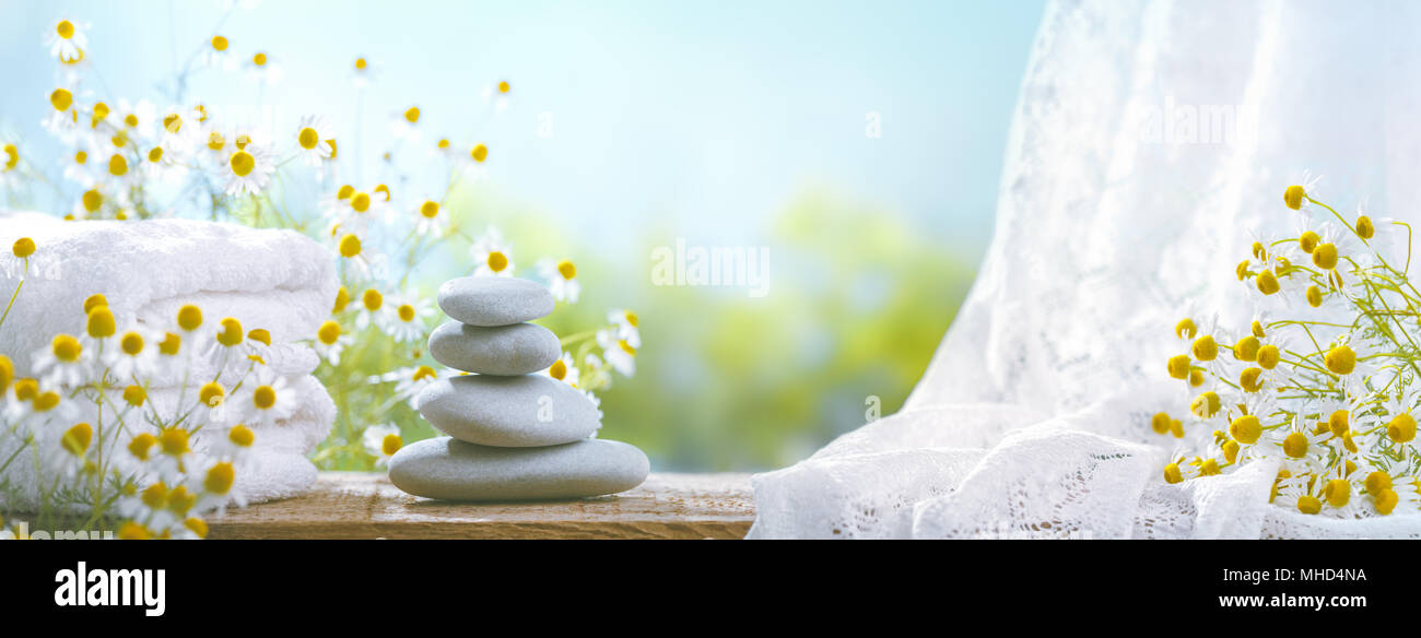 Spa still life with stack of stones,towel and chamomile flower. Stock Photo