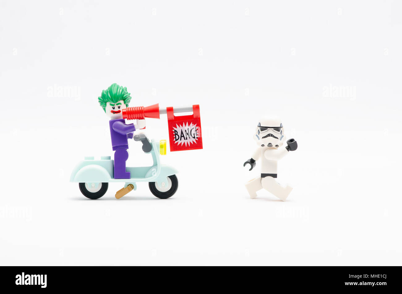 mini figure of joker riding scooter with bang gun chasing storm trooper. Lego minifigures are manufactured by The Lego Group. Stock Photo
