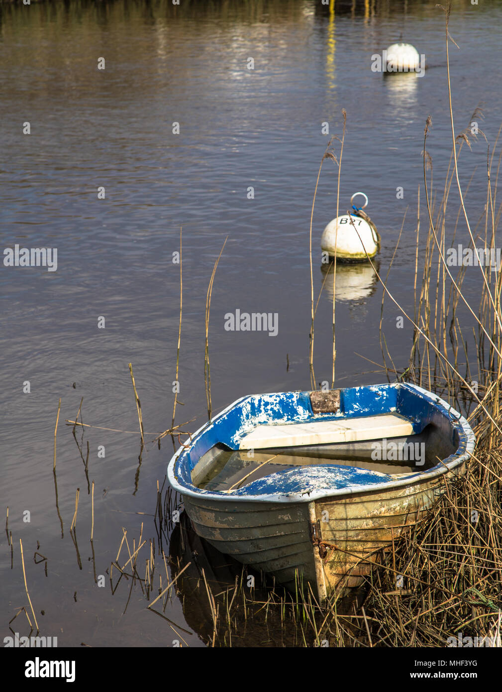 Boat floating on River with Buoys beyond. Peaceful, artistic image Stock Photo