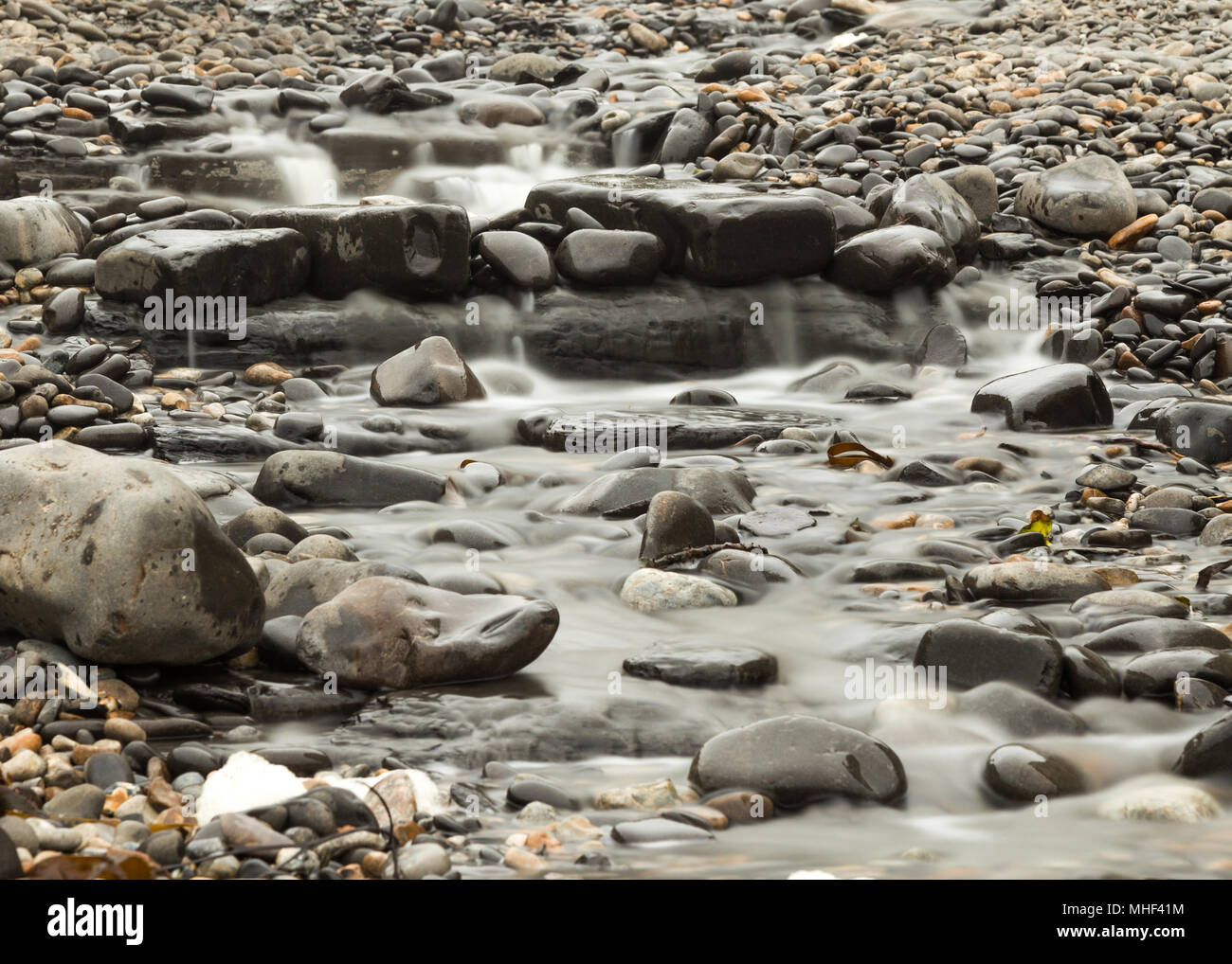 Stream with water flowing over rocks and stones Stock Photo