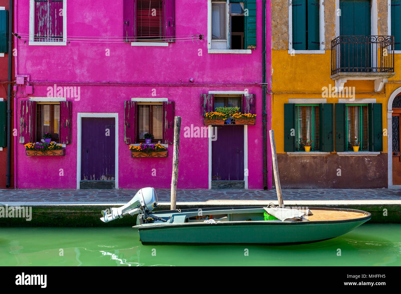 Boat on narrow canal in front of colorful houses of Burano, Italy. Stock Photo