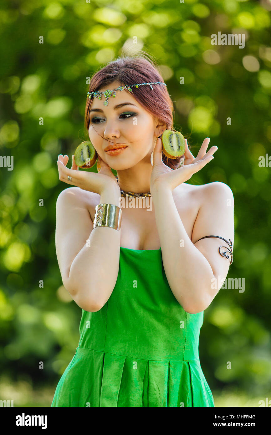 Portrait of a beautiful young asian woman holding two halves of kiwi ...