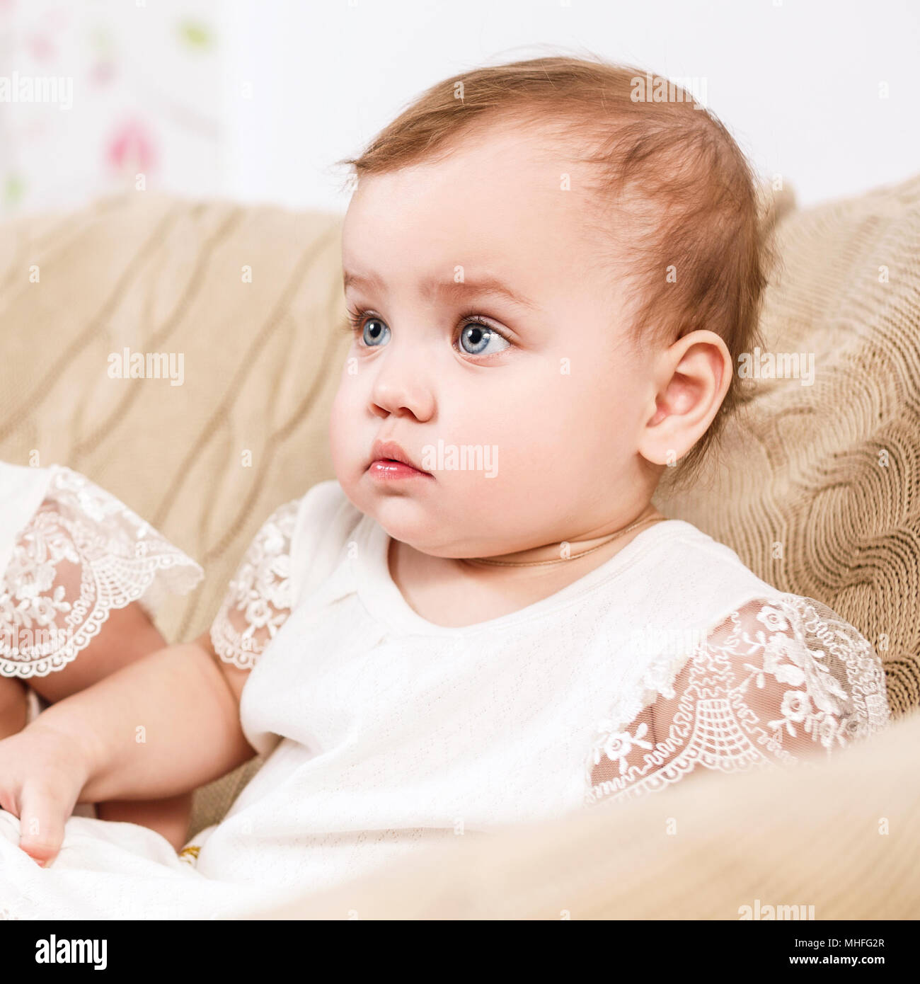 Cute little baby girl sitting in the chair. Stock Photo