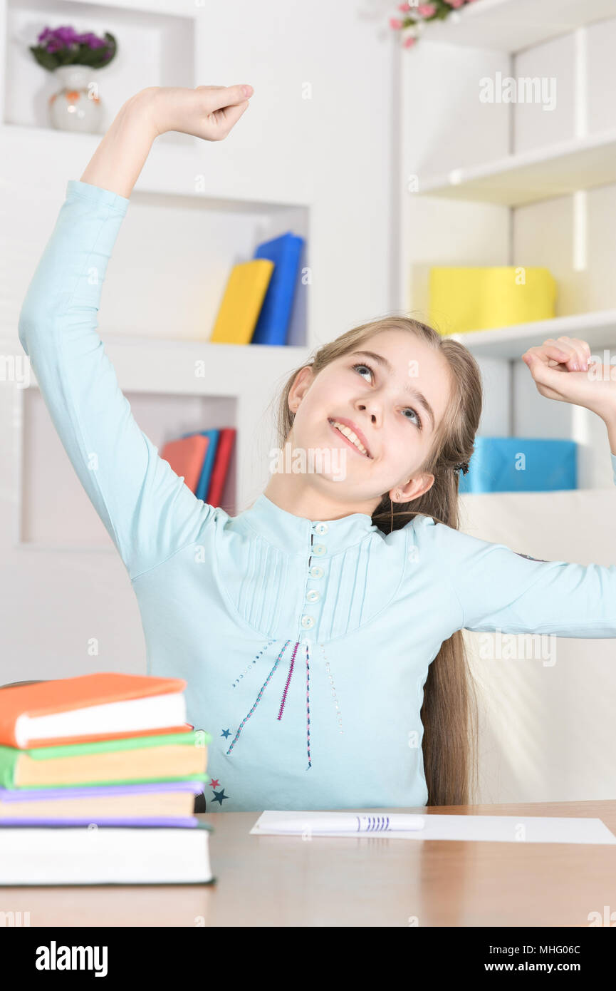 Cute schoolgirl sitting at table and studying Stock Photo - Alamy