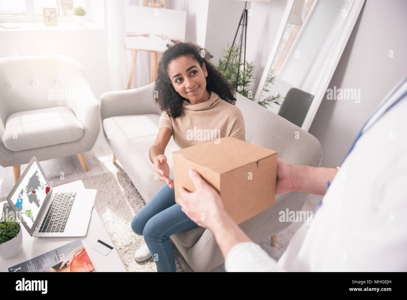Joyful nice woman sitting on the sofa Stock Photo