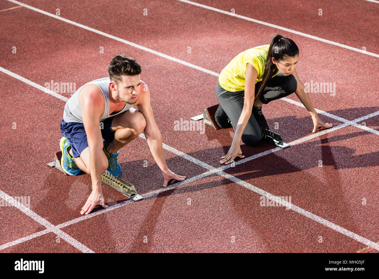 Male and female athlete in starting position at starting block Stock Photo