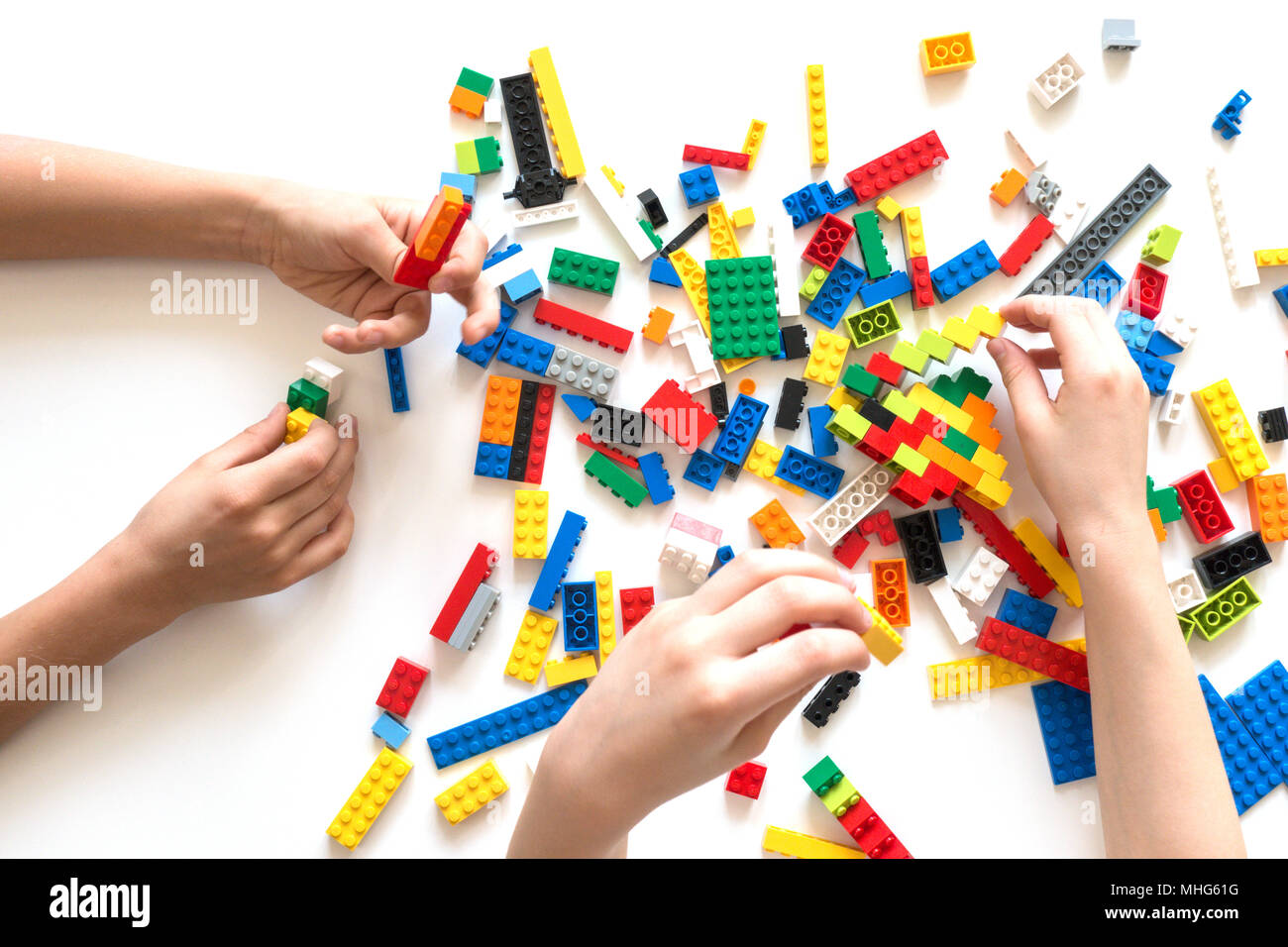 Children hands play with colorful lego blocks on white table. Stock Photo