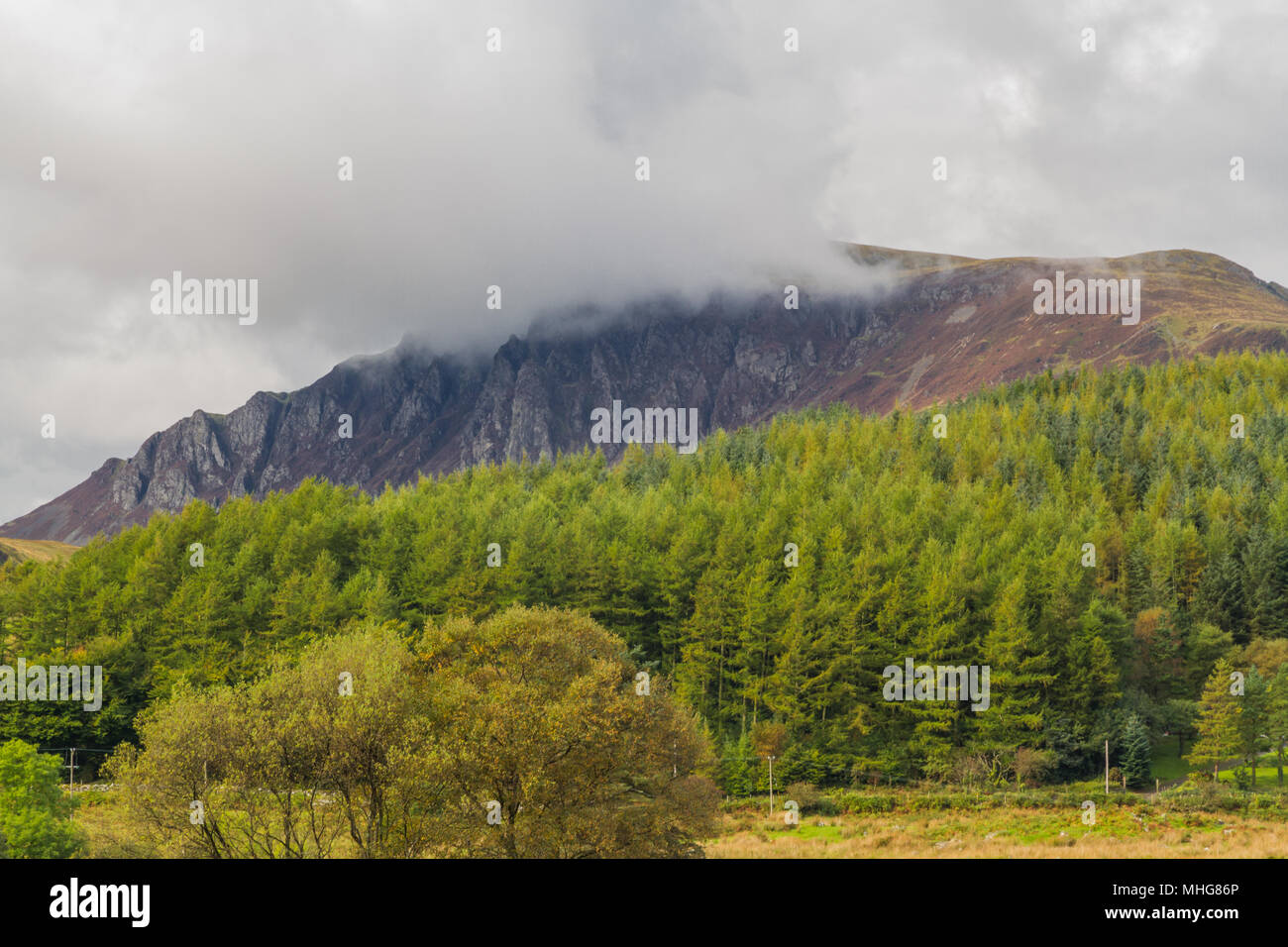 Striking cliffs of Craig Y Bera, on Mynydd Mawr, with low cloud seen from Rhyd Ddu, North Wales, United Kingdom. Stock Photo