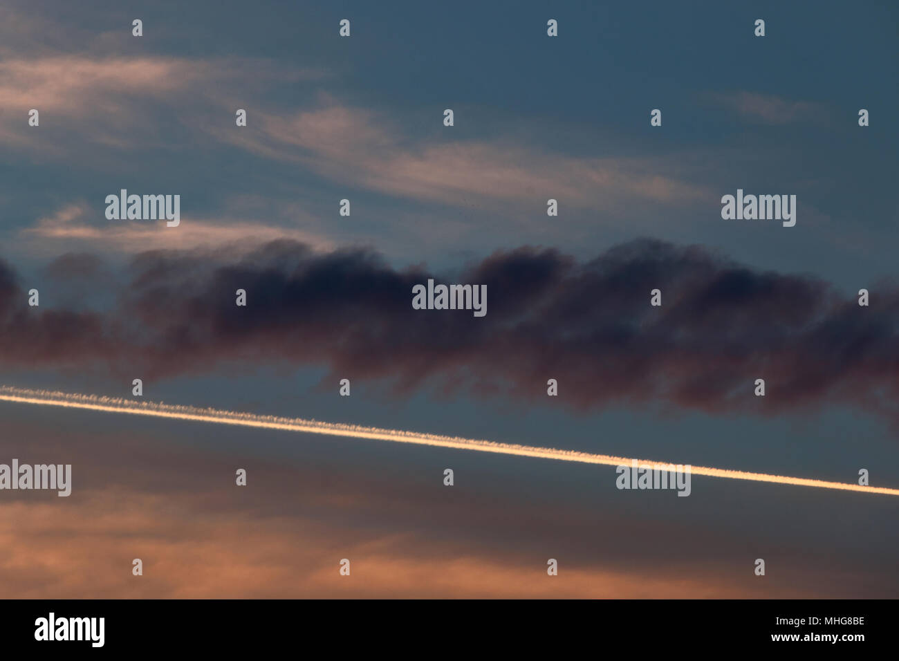 Plane trail at the sunset in the Roman sky, the saturated color clouds against the white diagonal line ,graphic effect Stock Photo