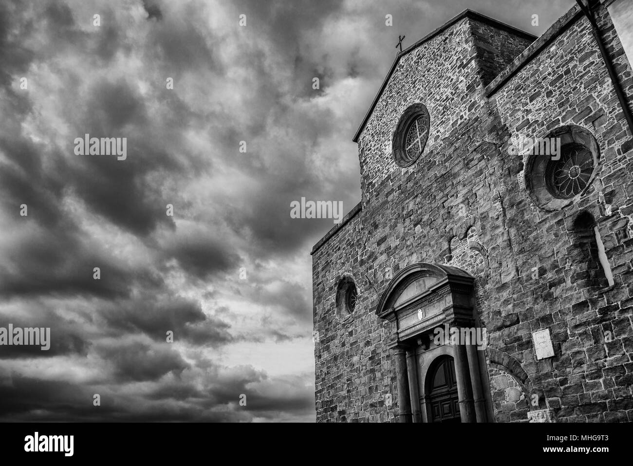 Cortona beautiful medieval cathedral in Tuscany with dramatic cloudy sky (Black and White with copy space) Stock Photo