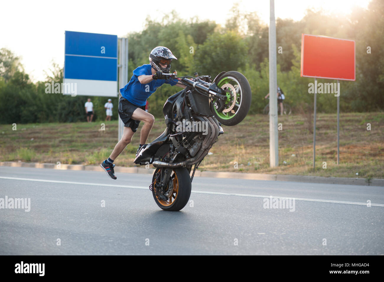 Ivano-Frankivsk, Ukraine - 9 August 2015: Sideview of moving biker making extremely dangerous stunt on his fast sport motorcycle. Doesn't feel fear,feeling confident, having expirience. Stock Photo